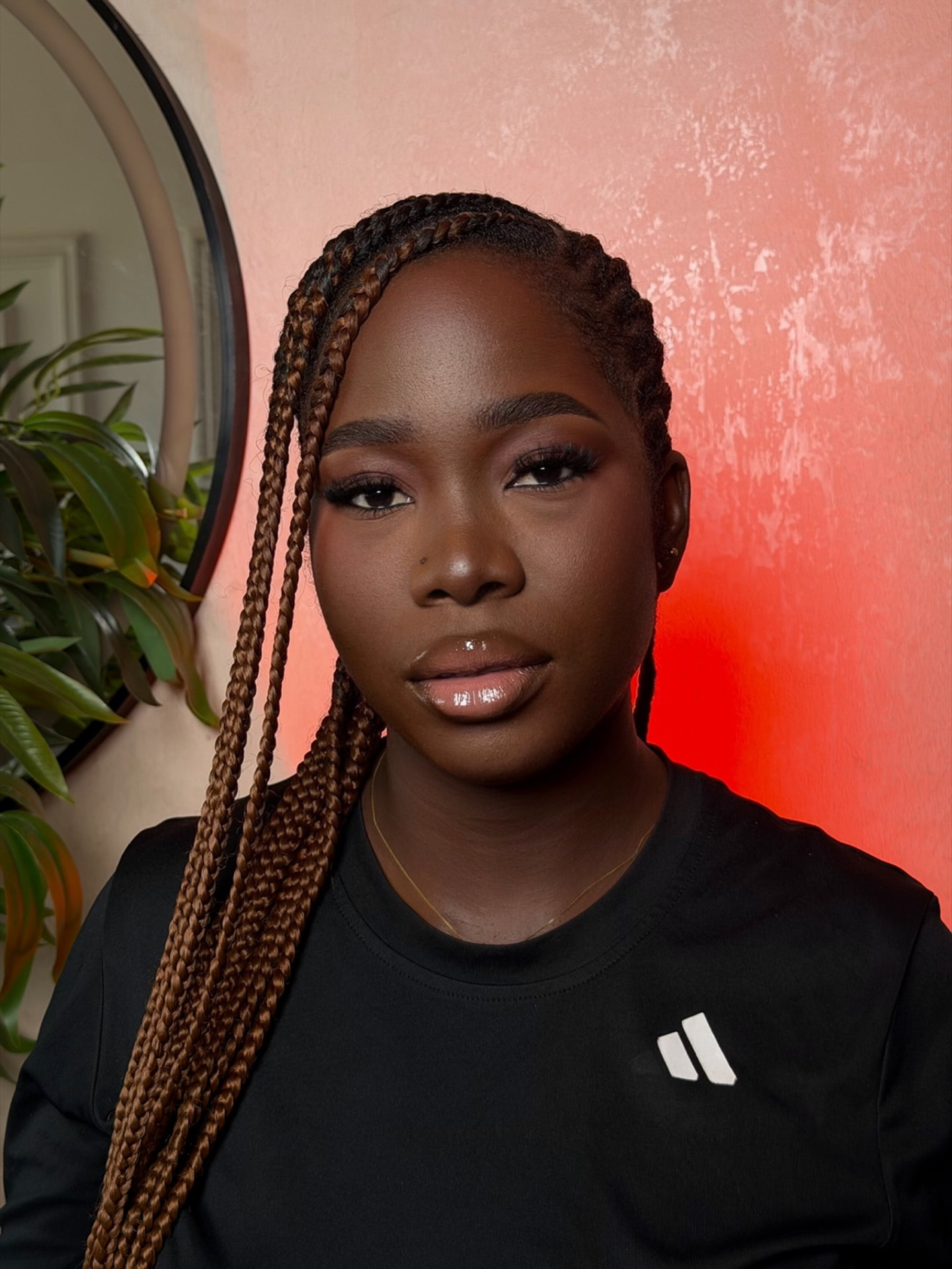 Soft glam with braids against a red wall